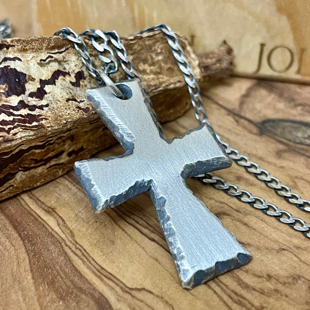 Oxidized Sterling silver Cross pendant on oxidized sterling silver chain sitting on wood display.