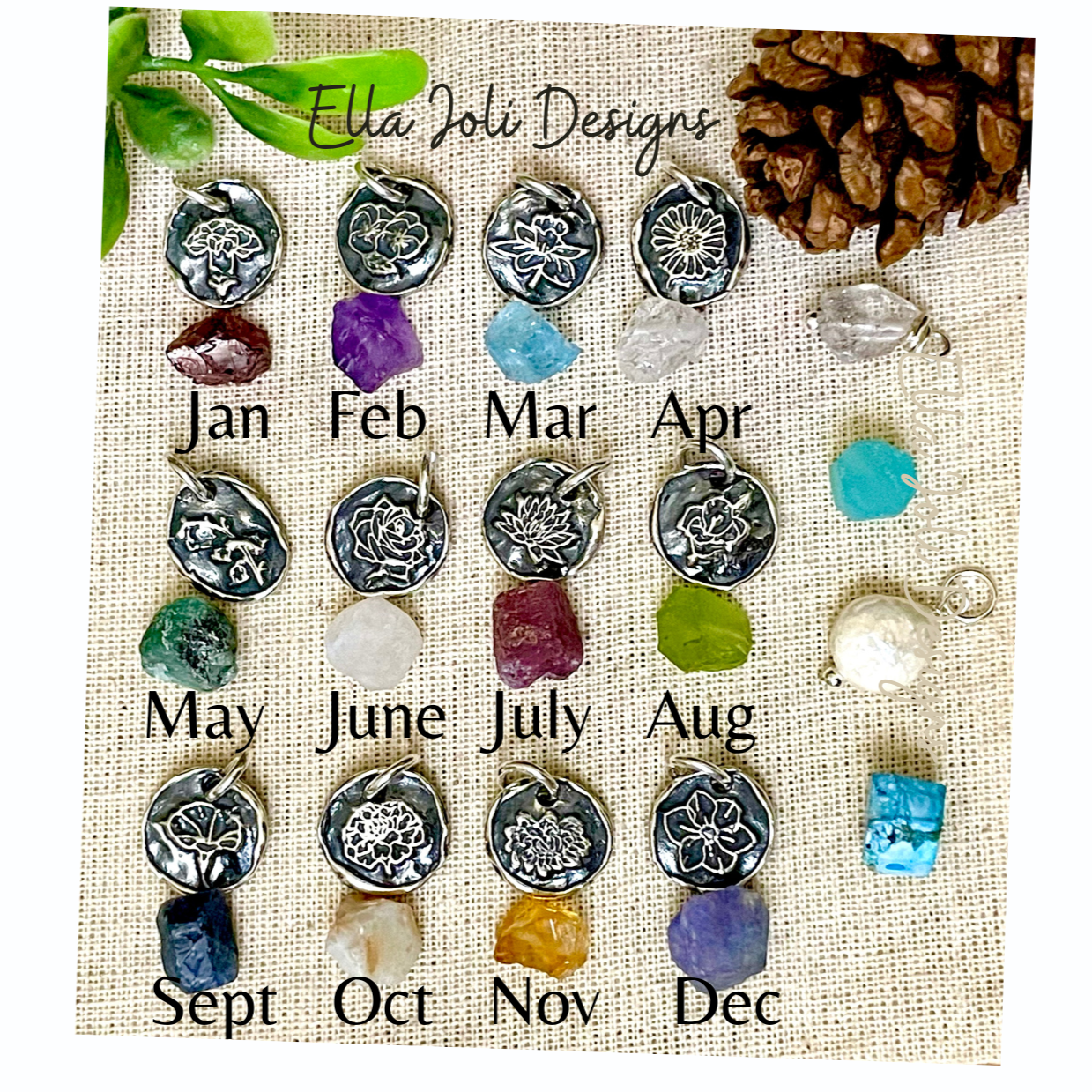 Collection of birthstones and charms on a display card with months labeled, branded 'Ella Joli Designs'.