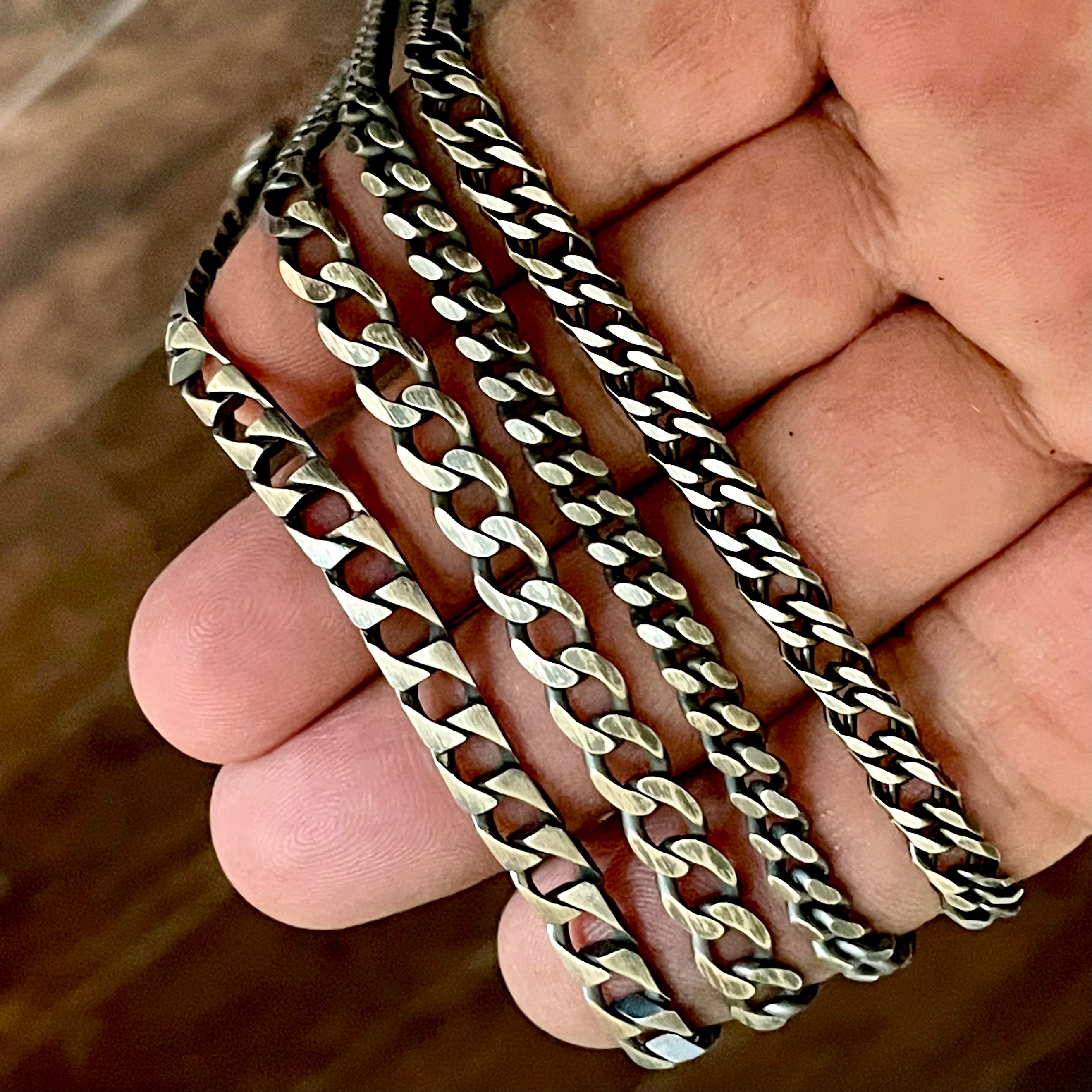 Silver chains held in a hand with a blurred background