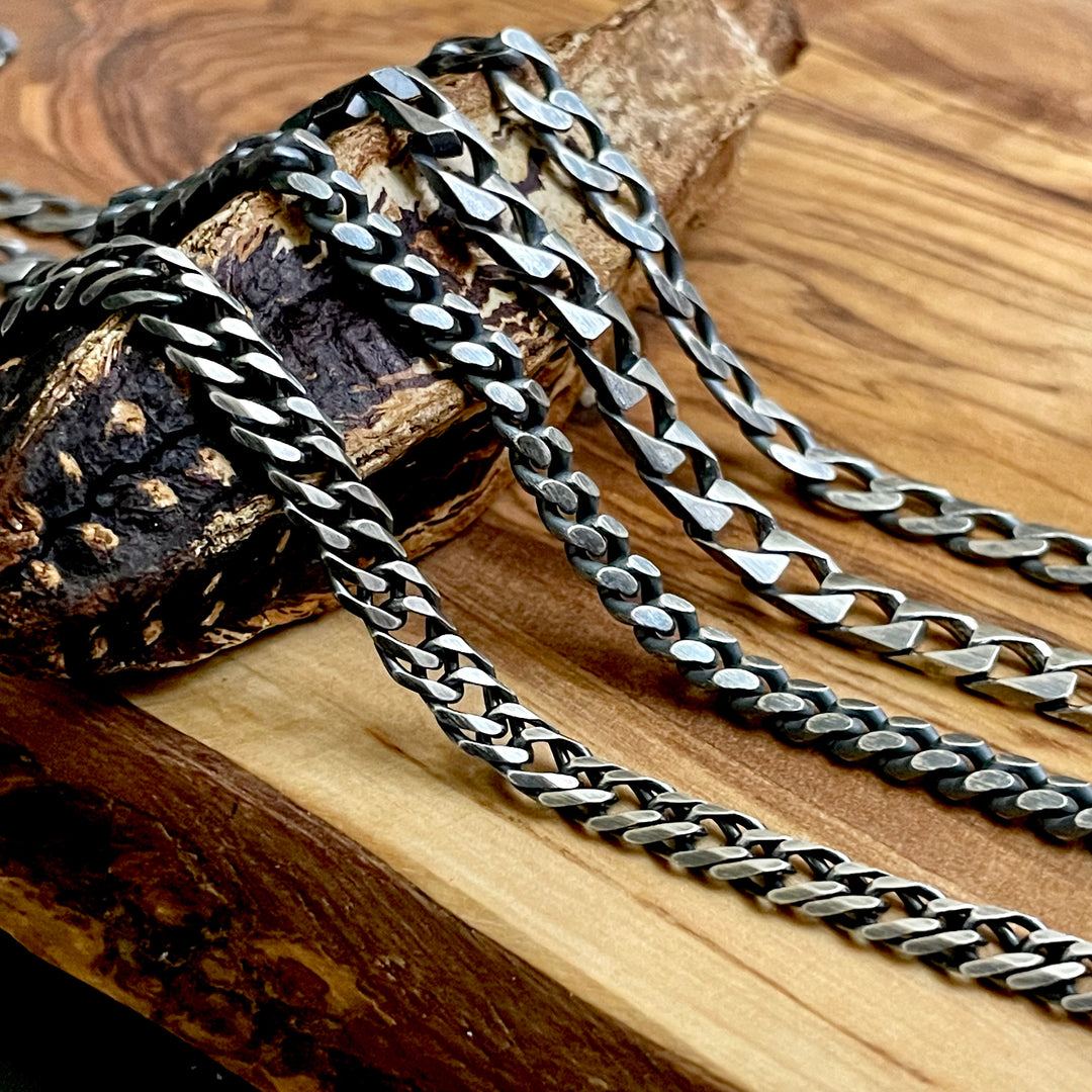 Silver chain necklaces on a wooden surface