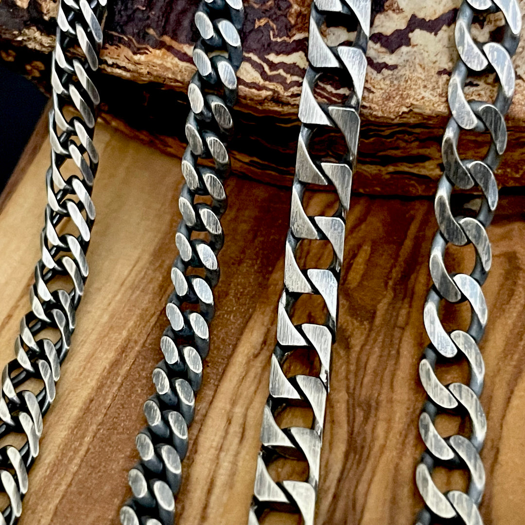 Silver chain necklaces on a wooden surface