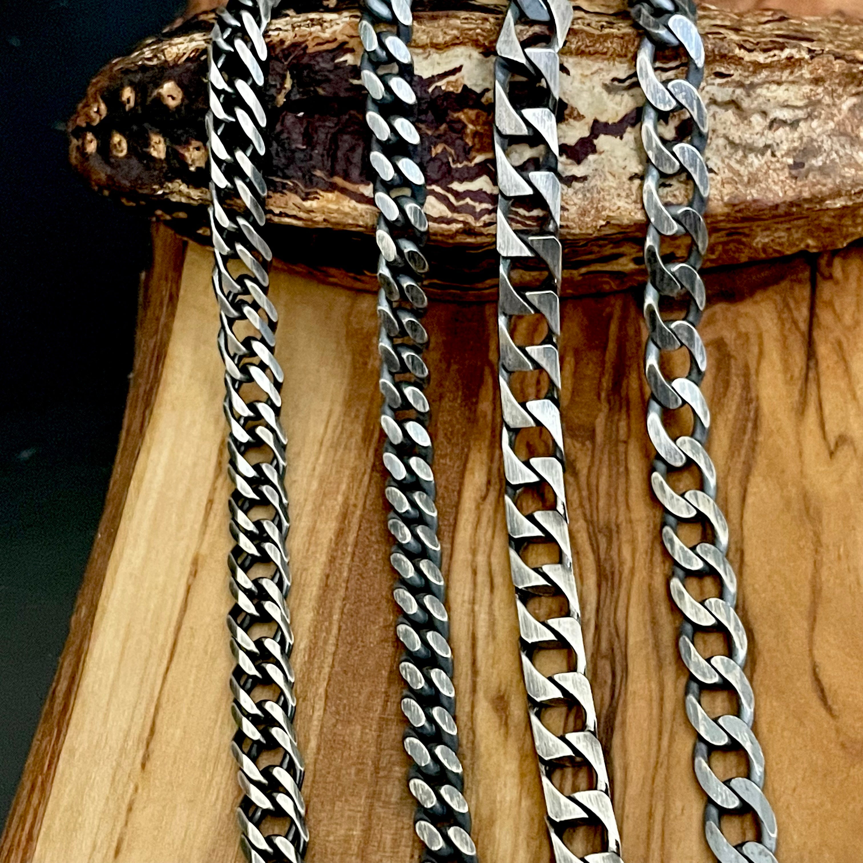 Four silver chain necklaces on a wooden stand