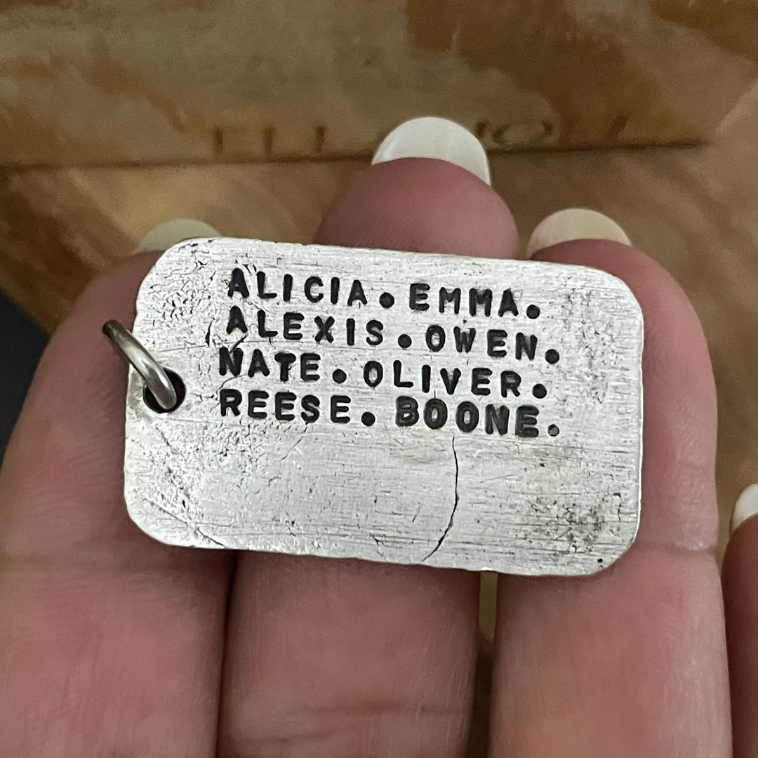 Sterling Silver rectangle shaped pendant Back side showing custom names of children and grandchildren. Held in hand. Handmade by Ella Joli