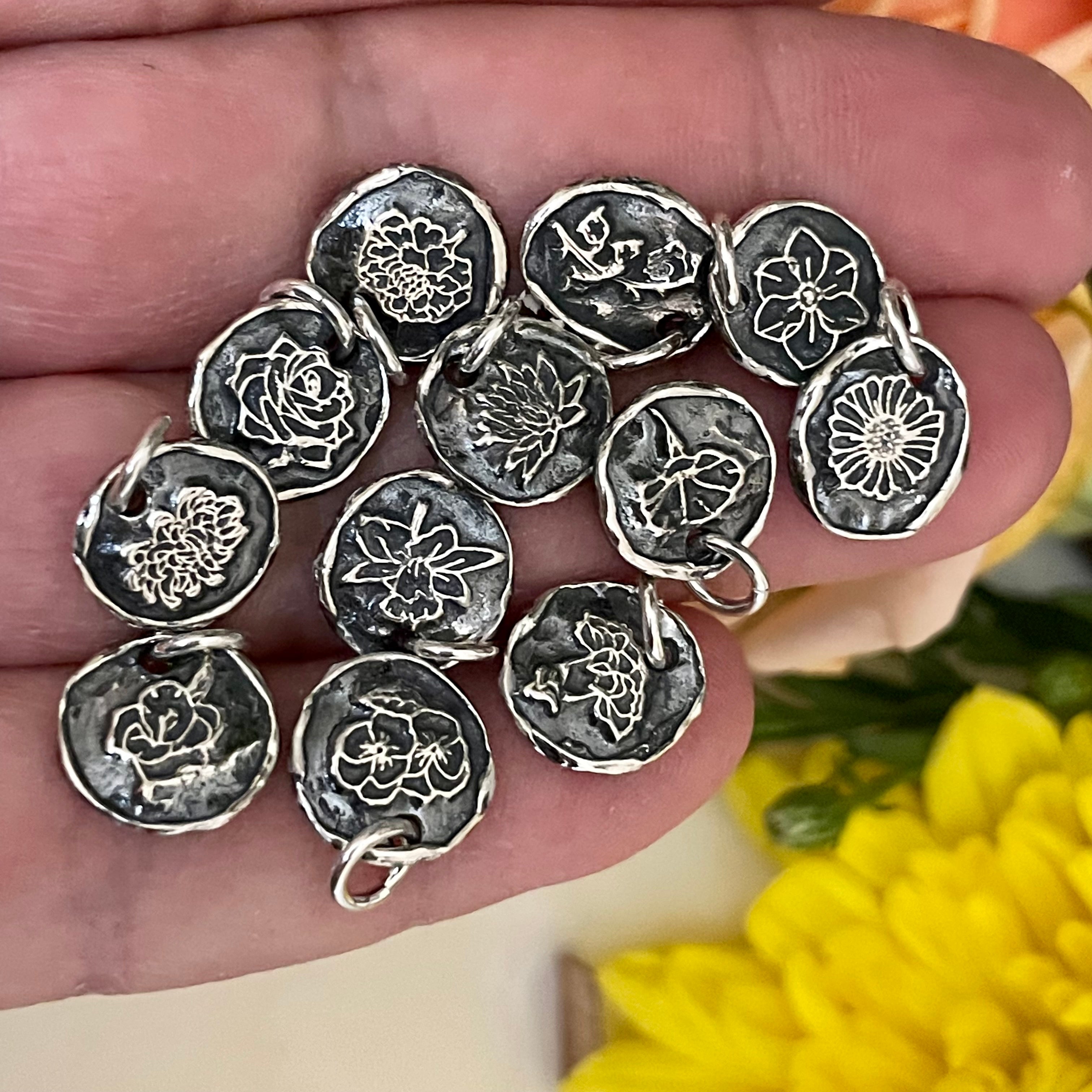 Silver floral designs held in a hand with yellow flowers in the background