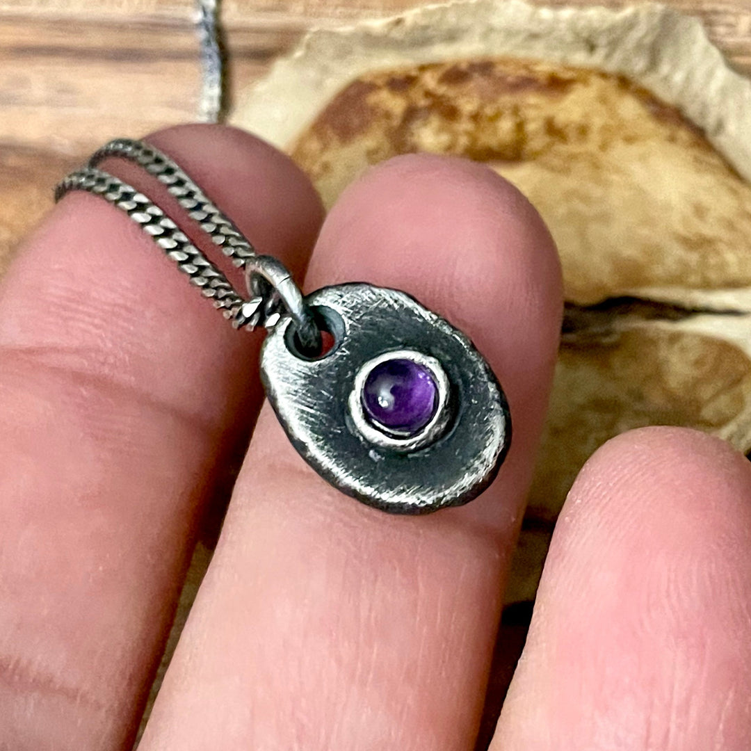 February purple amethyst oval shaped birthstone pendant on chain necklace in hand 