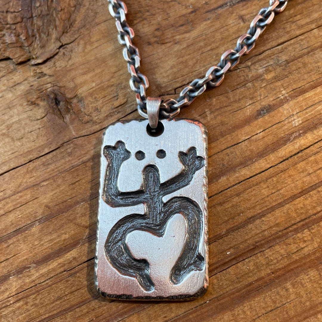 your personalized image logo or art carved into a silver rectangle pendant with a sterling silver cable chain laying on wood background. This custom image shows a frog. Handcrafted by Ella Joli