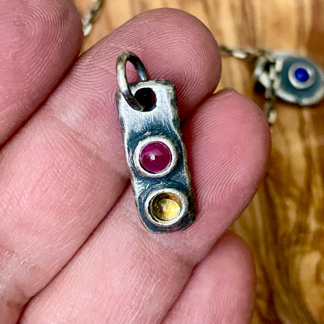Sterling silver red and gold gemstone pendant shown in hand