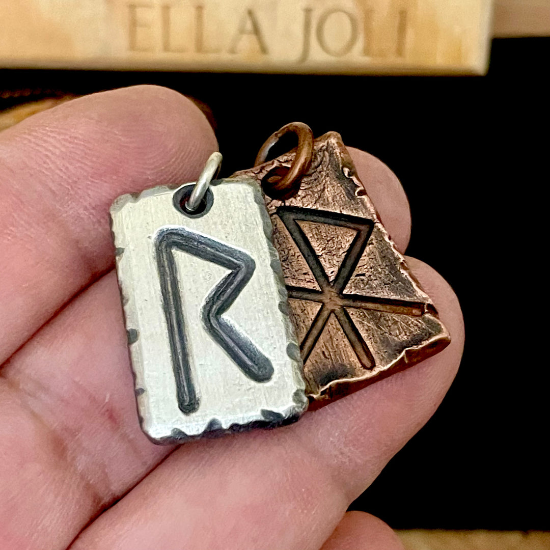 One sterling silver pendant and one pure copper pendant shown in hand. Both are engraved with hand forged rune symbols. 