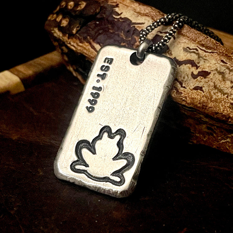 custom logo pendant with custom engraved established date of 1999 and a frog image in bottom right corner. all personalized with your artwork and dates on rectangle sterling silver pendant. Shown with sterling silver chain on wood background by Ella Joli
