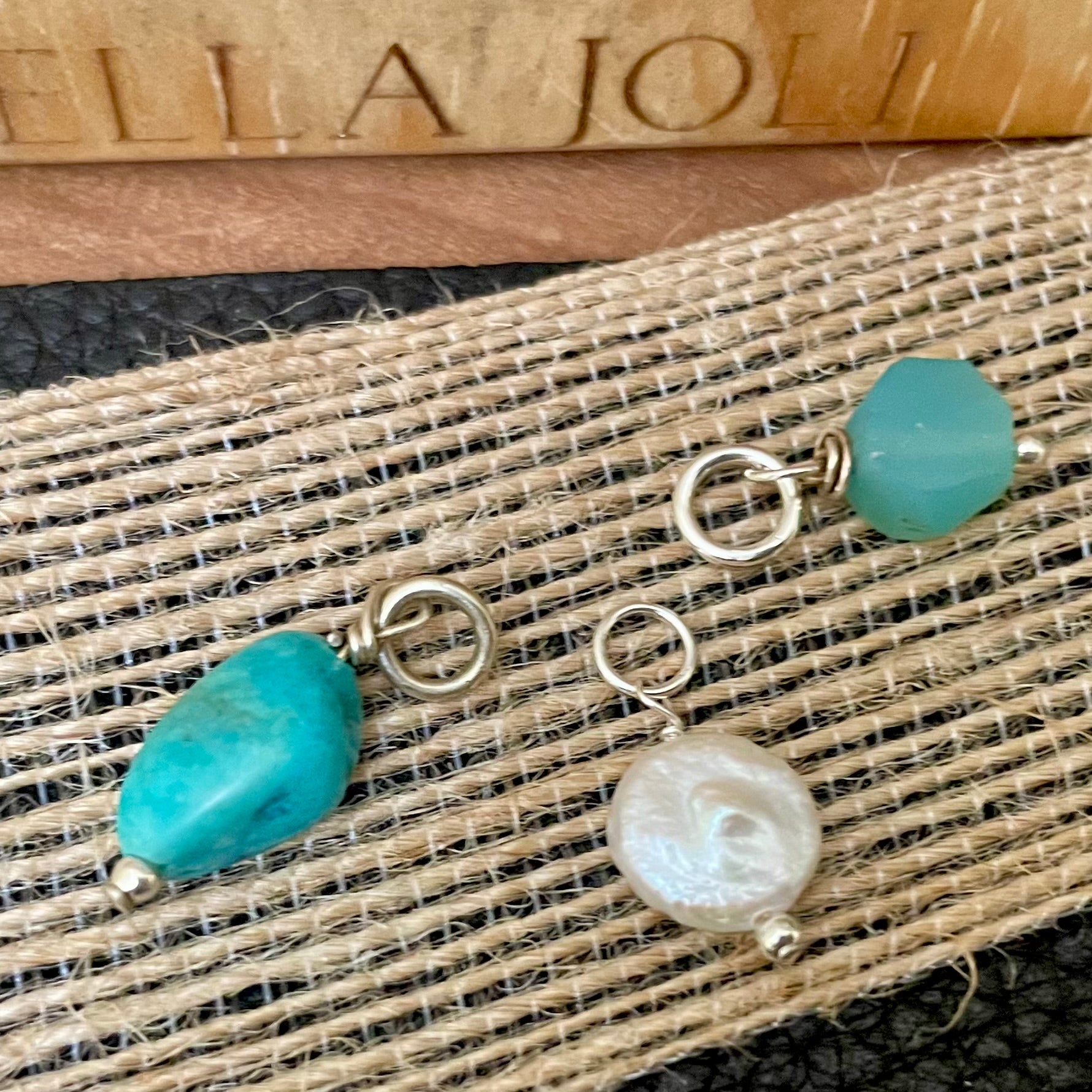 Assorted natural birthstone charms shown on wood background