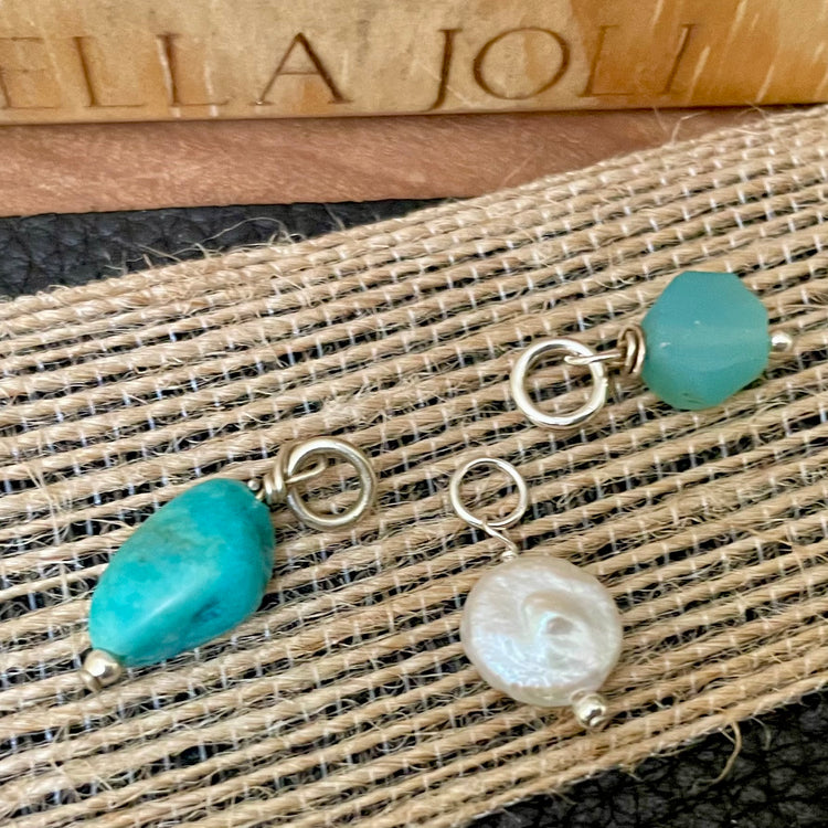 Assorted natural birthstone charms shown on wood background