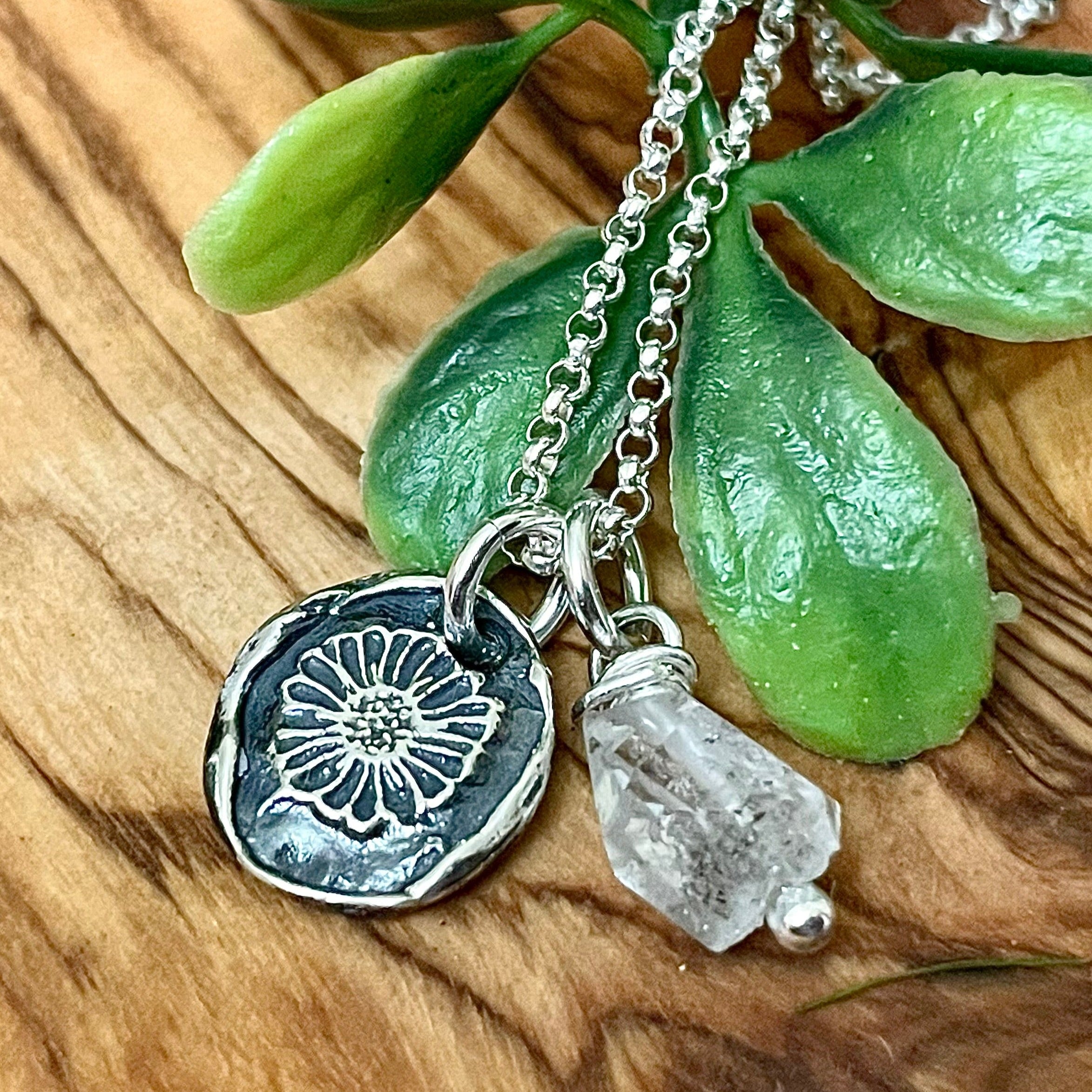 Handmade sterling silver daisy necklace with natural april birthstone on wood background