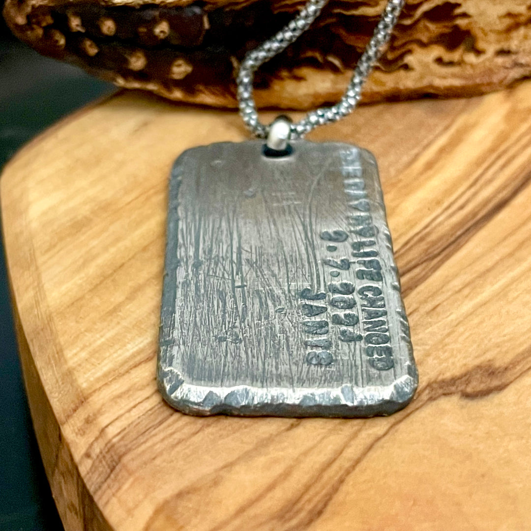 Flat laid view of rustic sterling silver engraved large pendant on silver chain displayed on wood background