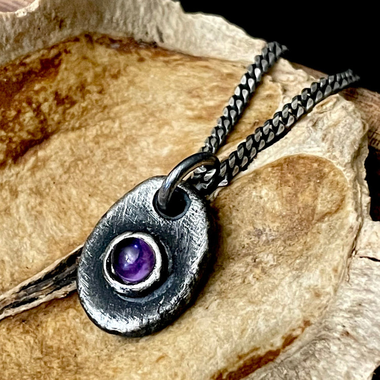 Oval rustic oxidized sterling silver amethyst gemstone pendant with sterling silver chain on wood background.