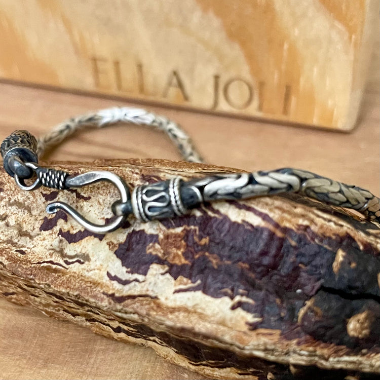 silver oxidized bali chain bracelet sitting on brown display. Hook clasp stands out. 
