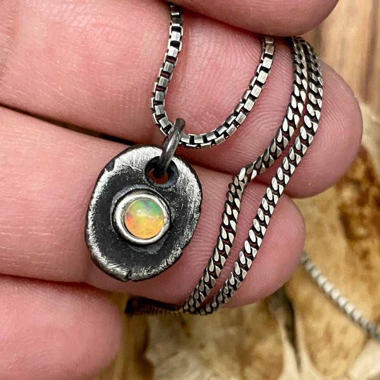 Oxidized sterling silver opal pendant hanging from box chain on hand