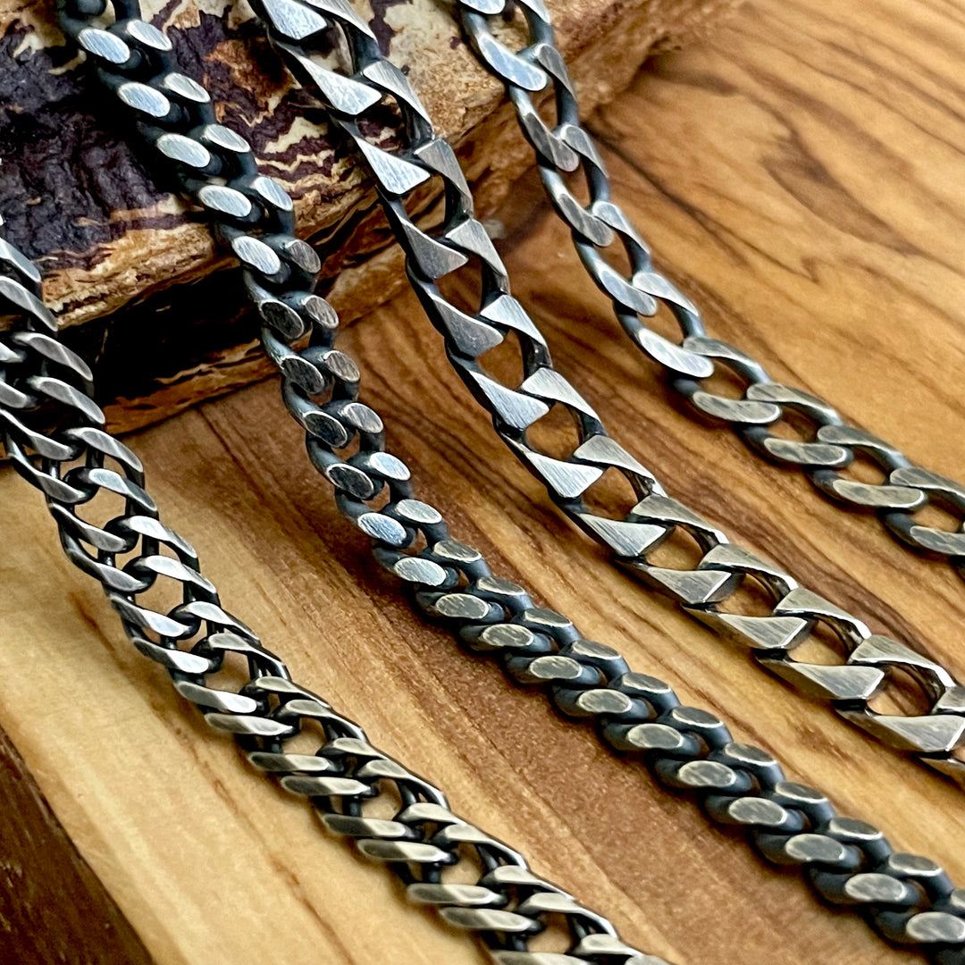four oxidized sterling silver curb chain necklace styles laying on wood display