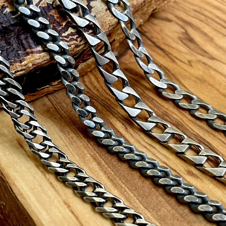 four oxidized sterling silver curb chain necklace styles laying on wood display