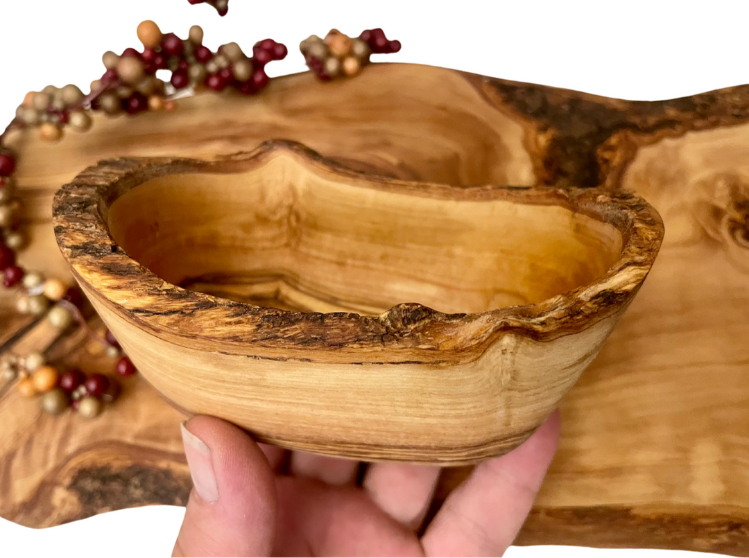 Olivewood bowl in hand with board in background