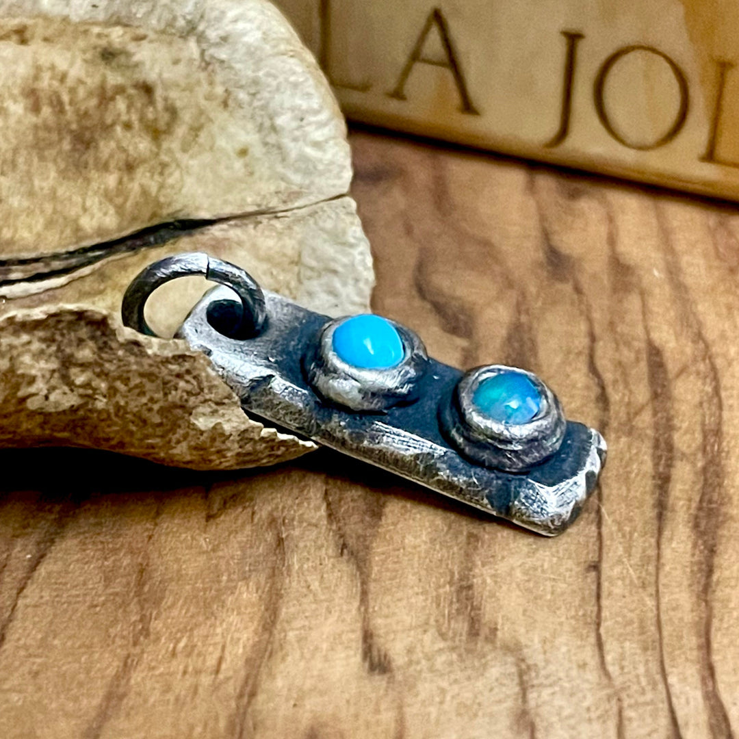 antique silver birthstone bar pendant with two blue gemstones on wood surface