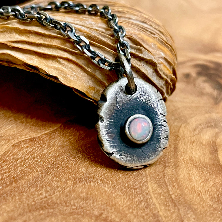 Opal pendant in oval shape on oxidized silver chain on wood background