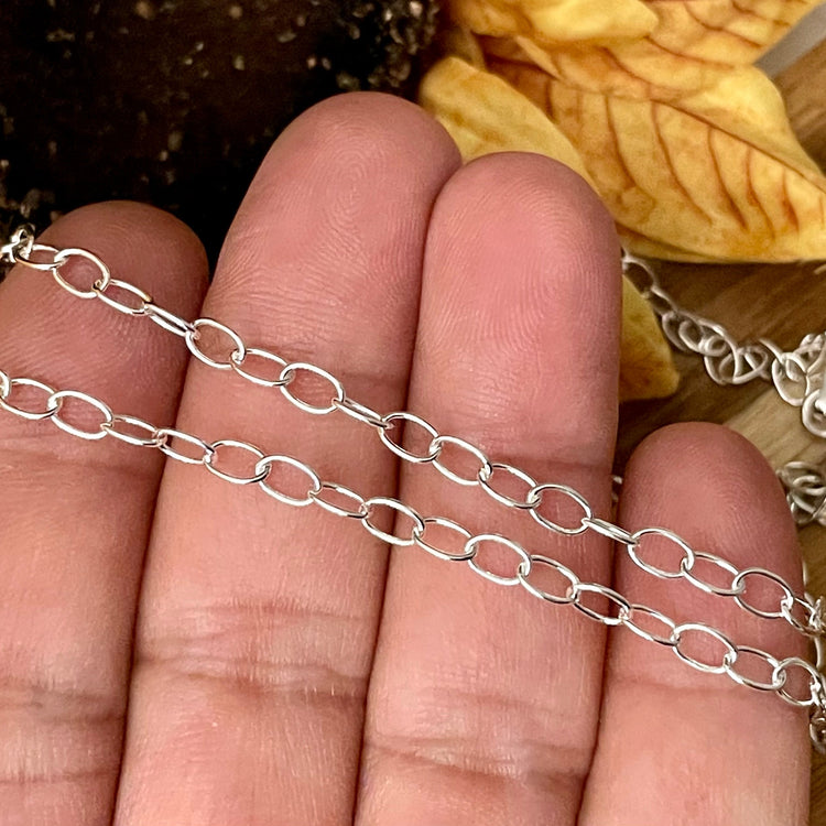 Silver chain necklace on a hand with a natural background