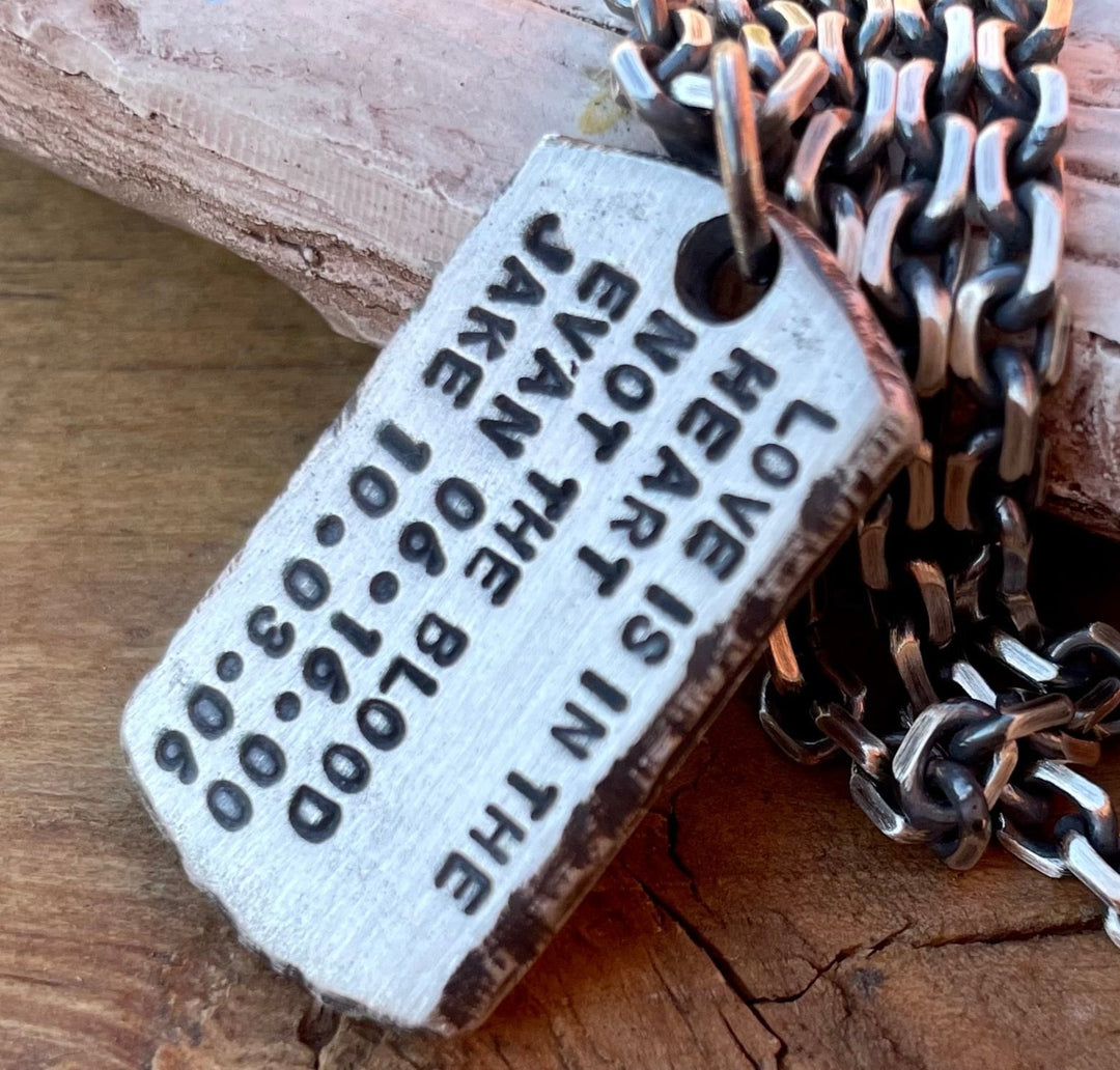 Custom Dog Tag for Men in Solid Sterling Silver hand carved and personalized with hand struck text. Shown on wood background. 