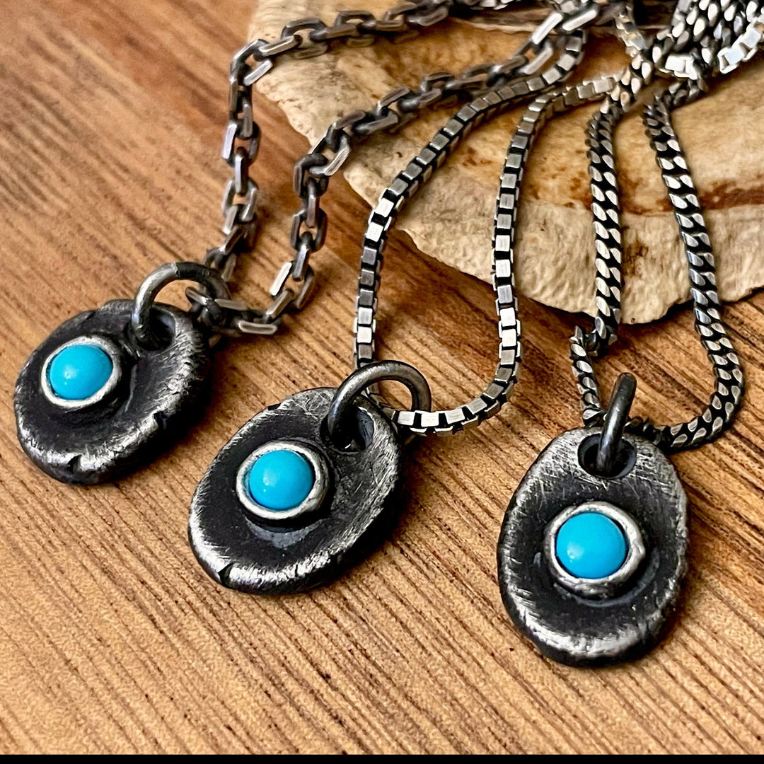 Three turquoise necklaces shown on different chains with wood background