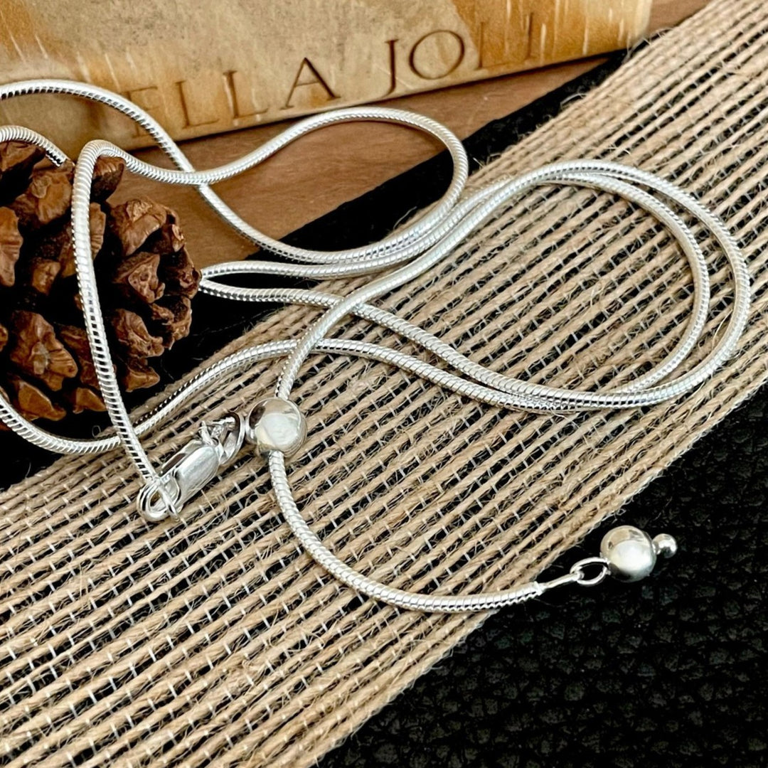Silver necklace with sliding bead for adjustment from 24 inches and shorter. Use with pendants, as a choker or layer it.  Displayed on a textured surface