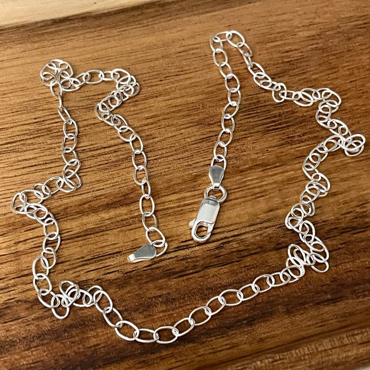 Silver chain necklace with 3.6mm oval links and sturdy lobster clasp displayed on a wooden surface