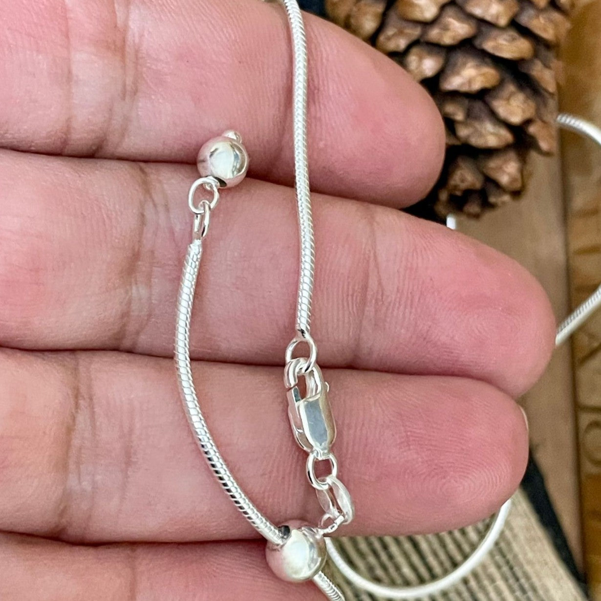 Adjustable sliding sterling silver snake chain necklace with bead pull for finding the perfect length. Shown in hand. 