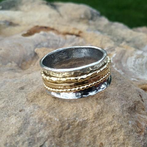 Sterling Silver and Gold Meditation Spinner Ring sitting on stone.