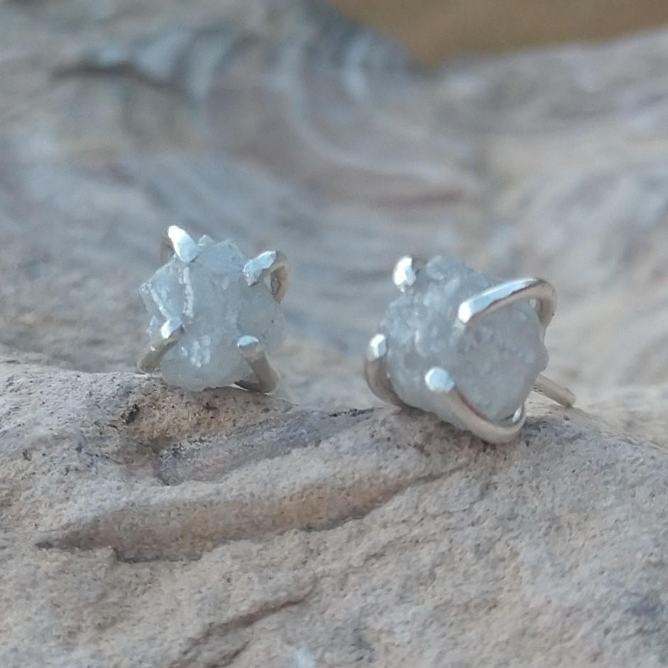 Natural diamond stud earrings in silver setting on stone