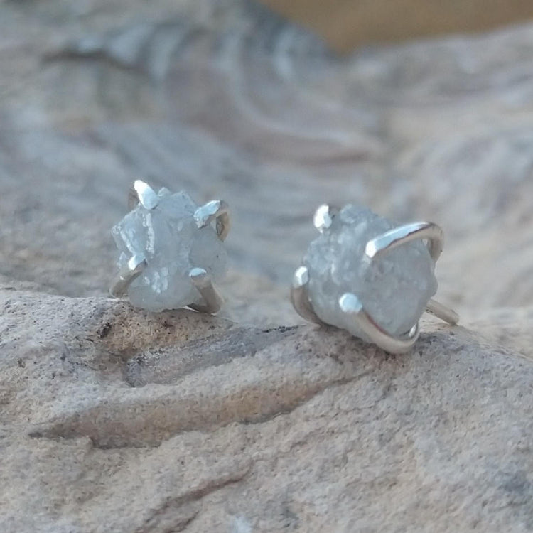 Natural diamond stud earrings in silver setting on stone