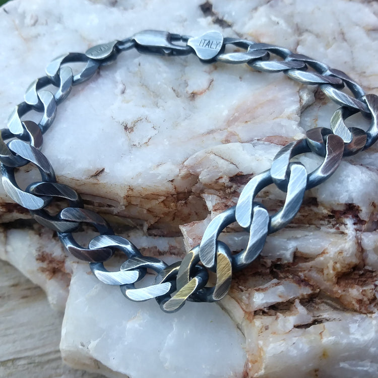 10mm oxidized sterling silver curb chain bracelet with lobster clasp, displayed on stone. 